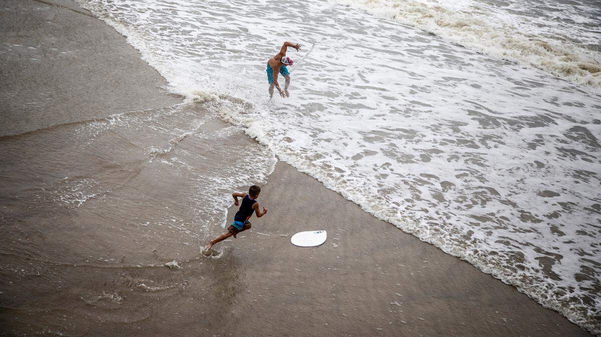 Skimboarders glide across the surf near the Ocean Crest Pier on Oak Island Monday, Aug. 3, 2020 as Tropical Storm Isaias moves towards the southeast coast. The storm is expected to strengthen to a hurricane before making landfall.