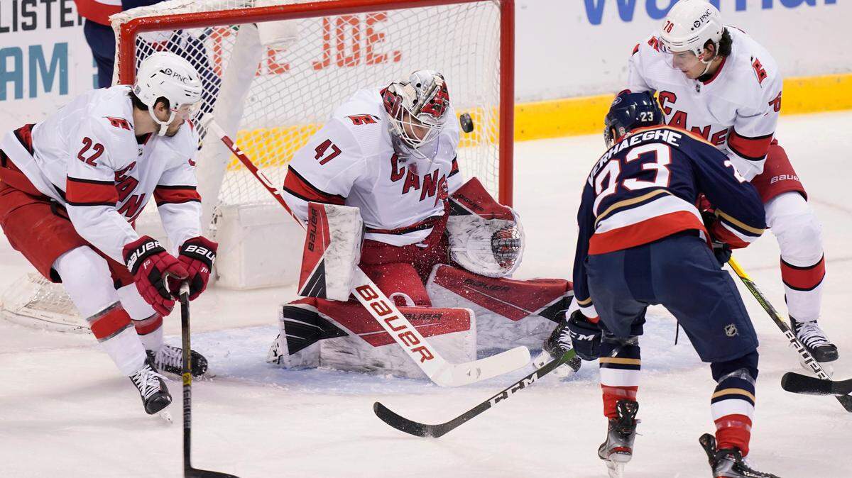 Carolina Hurricanes goaltender James Reimer (47) stops a shot by Florida Panthers center Carter Verhaeghe (23) during the first period at an NHL hockey game Saturday, Feb. 27, 2021, in Sunrise, Fla. Hurricanes defensemen Brett Pesce (22) and Brady Skjei (76) help defend. (AP Photo/Marta Lavandier)