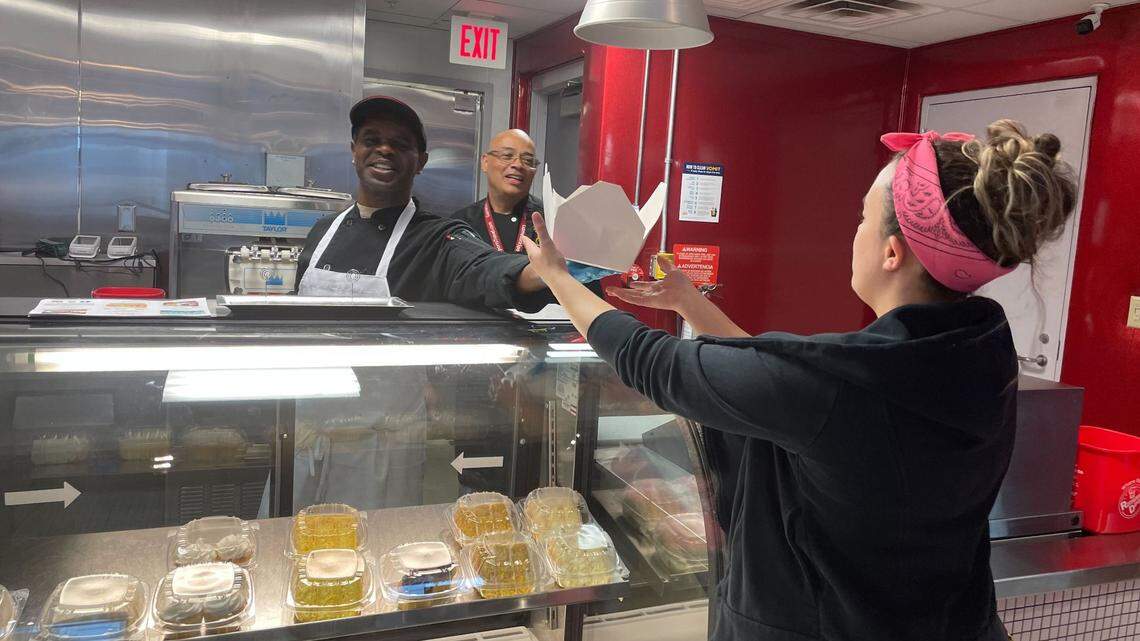 Morris Marshall, left, and Leroy Holley, right, hand over a lunch order to Natalie Carpiaux at Premier Cakes Diner at the NC Museum of History in downtown Raleigh on Feb. 16, 2023.