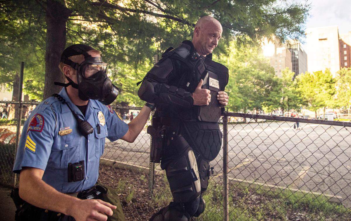 A police officer is helped by a colleague after being overcome with tear gas as police in riot gear deployed tear, gas pepper spray and smoke bombs against protesters near the intersection of McDowell and Davie Streets in downtown Raleigh Saturday, May 30, 2020.