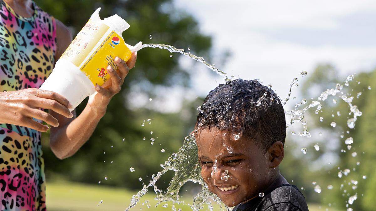 Allison Edwards, 10, pours water on Legend Hunt, 6, at Forest Hills Park on Monday, July 3, 2023, in Durham, N.C. Durham County public officials are trying to understand the resources residents have to respond to high temperatures.