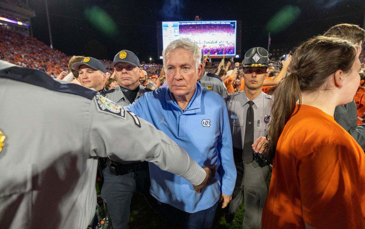 North Carolina coach Mack Brown is escorted off the field as Clemson fans take the field following the Tigers’ 31-20 victory on Saturday, November 18, 2023 at Memorial Stadium in Clemson, S.C.