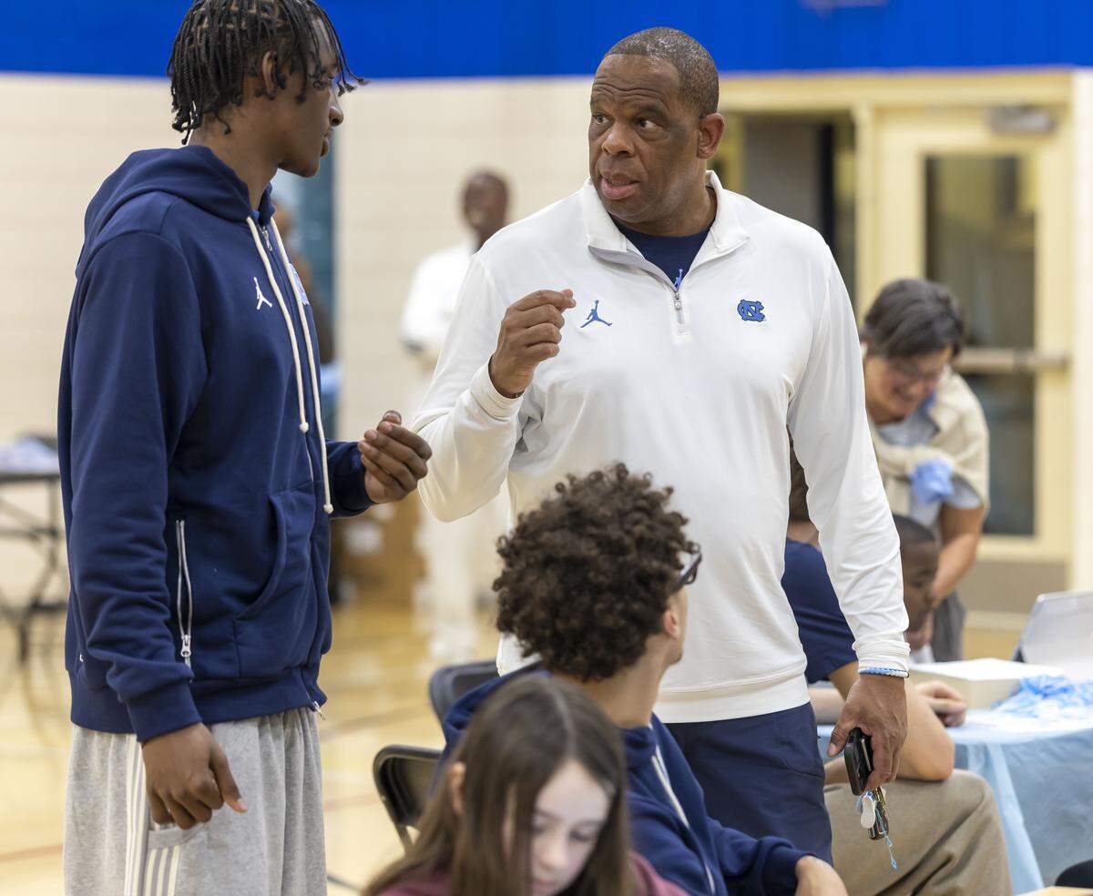 North Carolina coach Hubert Davis talks with players Isaiah Denis and Kyan Evans as the team works with children at Hargraves Community Center, designing t-shirts for Black History Month, on Wednesday, January 7, 2026 in Chapel Hill, N.C.  