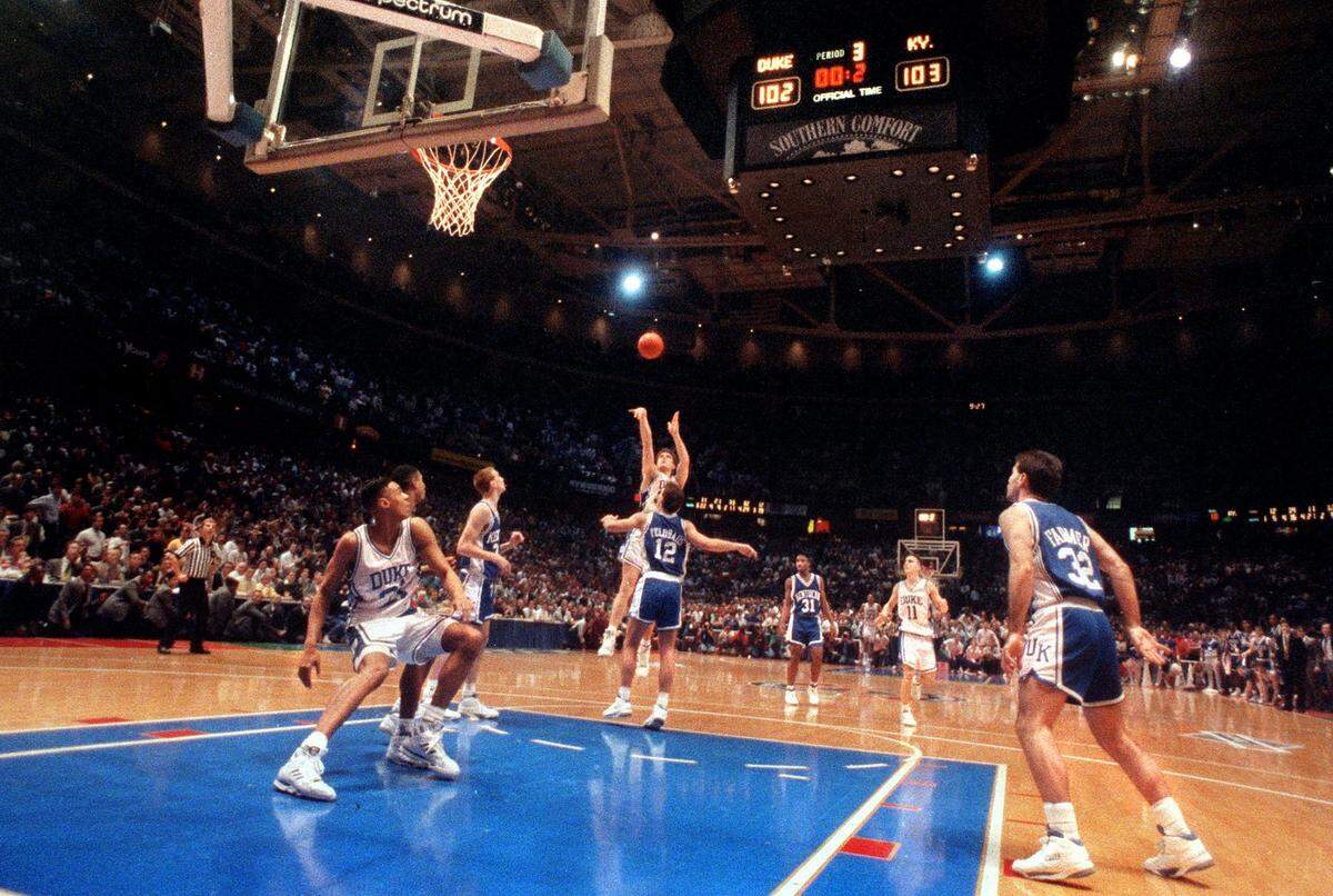 Duke’s Christian Laettner (32) fires up a shot over Kentucky’s Deron Feldhaus with .2 seconds left on the game clock to score and send the Blue Devils to the Final Four on March 28, 1992 beating the Wildcats in overtime 104-103. With 2.1 seconds remaining in overtime, defending national champion Duke trailed 103–102. Grant Hill threw a pass the length of the court to Laettner, who faked right, dribbled once, turned, and hit a jumper as time expired for the 104-103 win. 