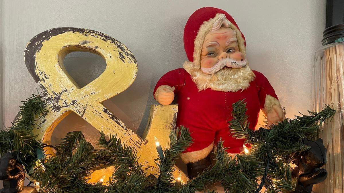 A vintage Santa has a place of honor on a mantel decorated for Christmas.