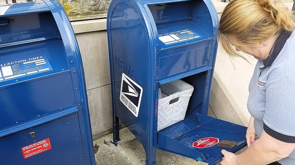 A U.S. Postal Service employee checks a blue mail collection box in this agency photo. Taxpayers and others across North Carolina have fallen victim to check-washing scams after their checks were deposited in the mail, stolen and cashed under a different name.