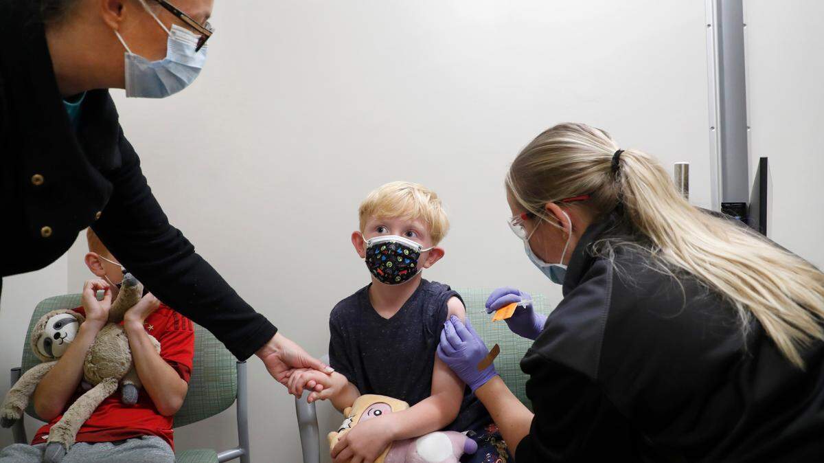 Kelly Baumberger of Apex holds the hand of her son Ethan, 5, as he gets a pediatric COVID-19 vaccine shot administered by Brigitta Bowers at UNC Children’s clinics in Raleigh, N.C., Thursday, Nov. 4, 2021. Son Lukas is to the left. In late October, the U.S. Food and Drug Administration authorized the emergency use of the Pfizer vaccine for children 5 to 11, who previously were not eligible for the shot.