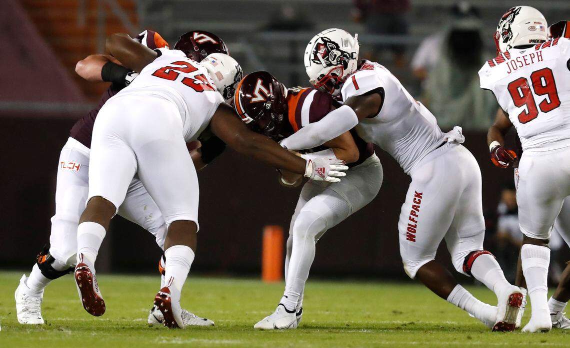 N.C. State linebacker Isaiah Moore (1), right, and Alim McNeill (29) tackle Virginia Tech quarterback Braxton Burmeister (3) during the first half of N.C. State’s game against Virginia Tech at Lane Stadium in Blacksburg, VA Saturday, Sept. 26, 2020.