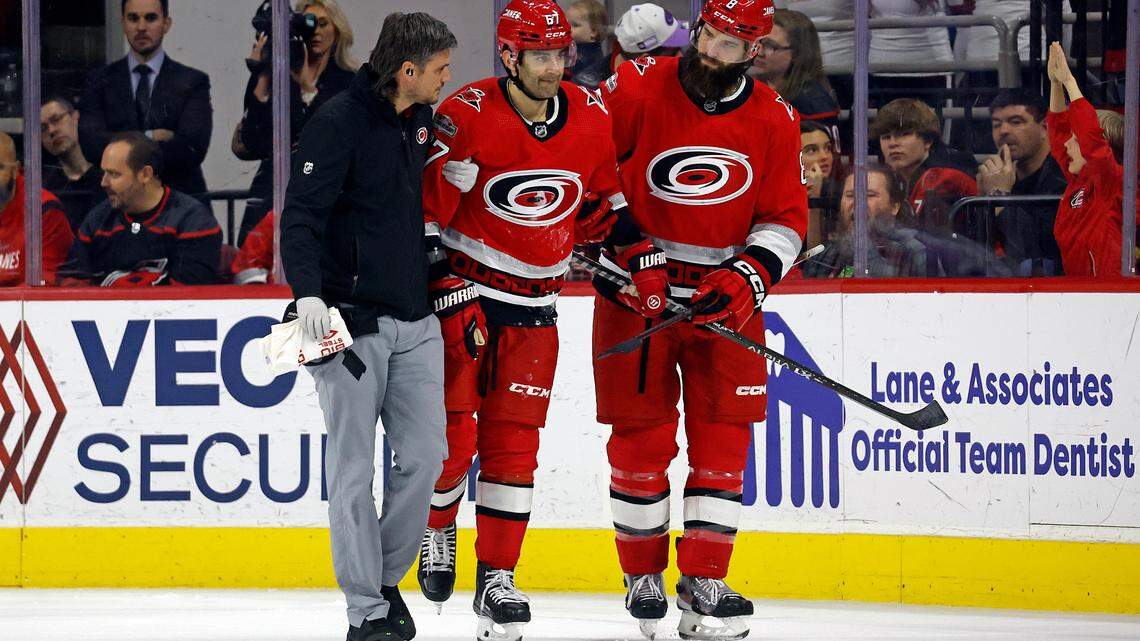 Carolina Hurricanes head athletic trainer Doug Bennett, left, and Brent Burns, right, assist Max Pacioretty off the ice following an injury during the third period of the team’s NHL hockey game against the Minnesota Wild in Raleigh, N.C., Thursday, Jan. 19, 2023. (AP Photo/Karl B DeBlaker)