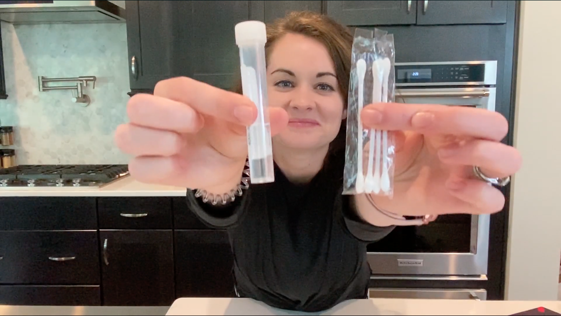 A woman demonstrates how to use the at-home test kit for COVID-19 known as Pixel by LabCorp. Students at Elon University in North Carolina are required to take the test, which costs $129, before classes resume.