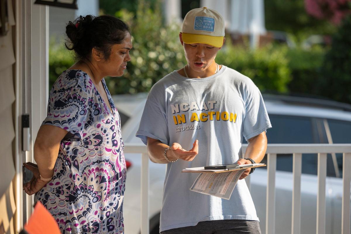 William Liu, a canvasser for North Carolina Asian Americans Together (NCAAT), talks with Latha Tenneti, explaining her voting options and inquiring about her top voting issues on Wednesday, July 31, 2024 in Morrisville, N.C.