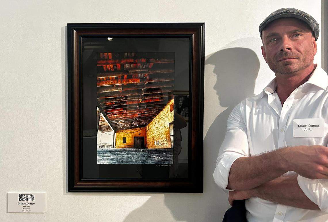 Stuart Dance poses with “Warm Colors,” the picture he took of Raleigh’s Charlie Goodnights building, which is part of an exhibition at Contemporary Art Museum