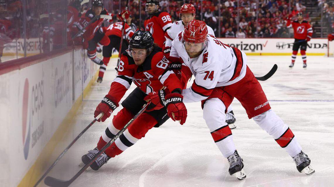 May 9, 2023; Newark, New Jersey, USA; New Jersey Devils center Jack Hughes (86) plays the puck while being defended by Carolina Hurricanes defenseman Jaccob Slavin (74) during the second period in game four of the second round of the 2023 Stanley Cup Playoffs at Prudential Center. Mandatory Credit: Ed Mulholland-USA TODAY Sports