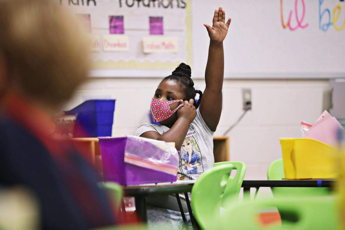 Ariel Williams raises her hand to answer a question in her first grade class where students work from spaced tables at Hunter Elementary School in Raleigh on Monday, October 26, 2020, on the first day back in school for some Wake students.