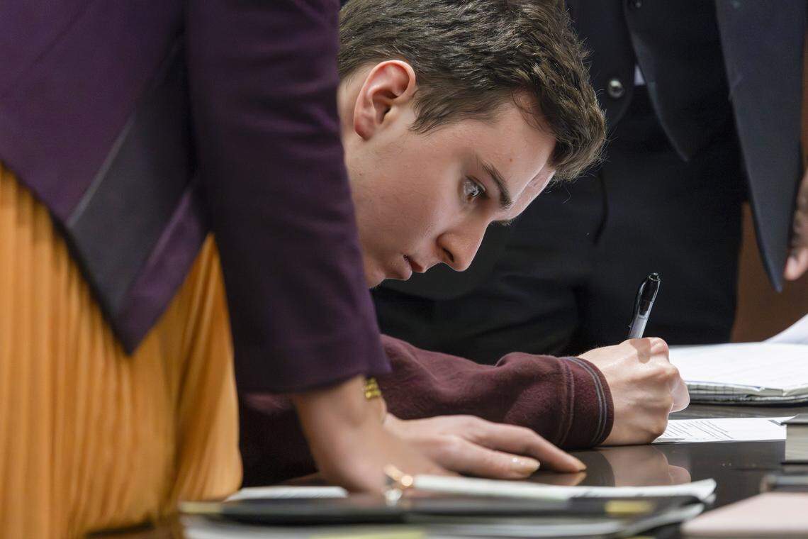 Austin Thompson, 18, signs documents formalizing his guilty plea in the 2022 Hedingham mass shooting case at the Wake County Justice Center in Raleigh on Wednesday, Jan. 21, 2026. He is charged with killing five people and injuring two others, the deadliest mass shooting in the city’s history.