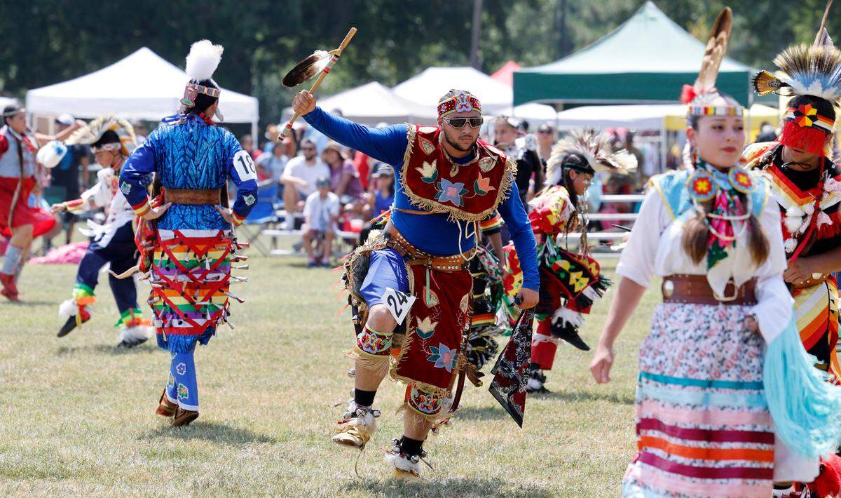 Marcus Mills of Hollister, center, a citizen of the Haliwa-Saponi Tribe, dances alongside other participants raising money for a family during a blanket dance at the Dix Park Inter-Tribal Pow Wow in Raleigh, N.C., Saturday, August 26, 2023.
