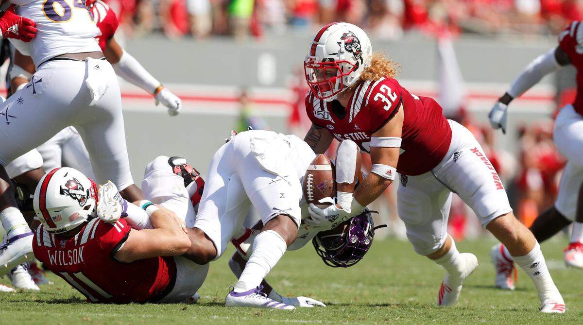 N.C. State’s Payton Wilson (11), left, and Drake Thomas (32) tackle East Carolina’s Demetrius Mauney (3) during the Wolfpack’s victory over the Pirates at Carter-Finley Stadium in 2019.