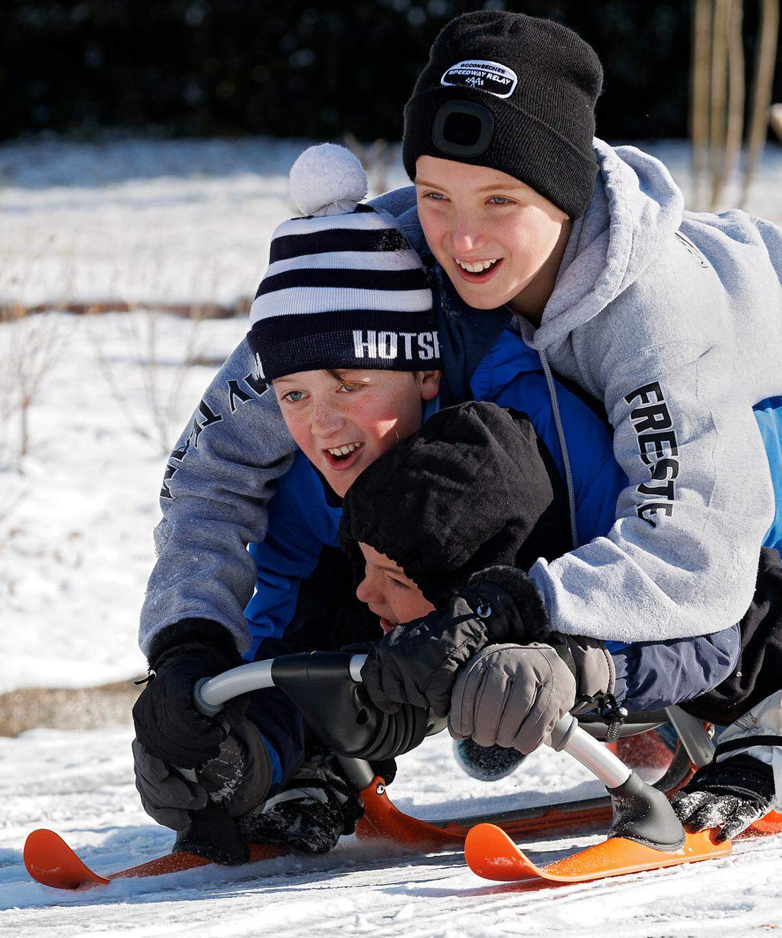 Caleb Wixted, Harris Travis and Sam Wixted sled down a hill in Durham, N.C. on Wednesday, Jan. 22, 2025.