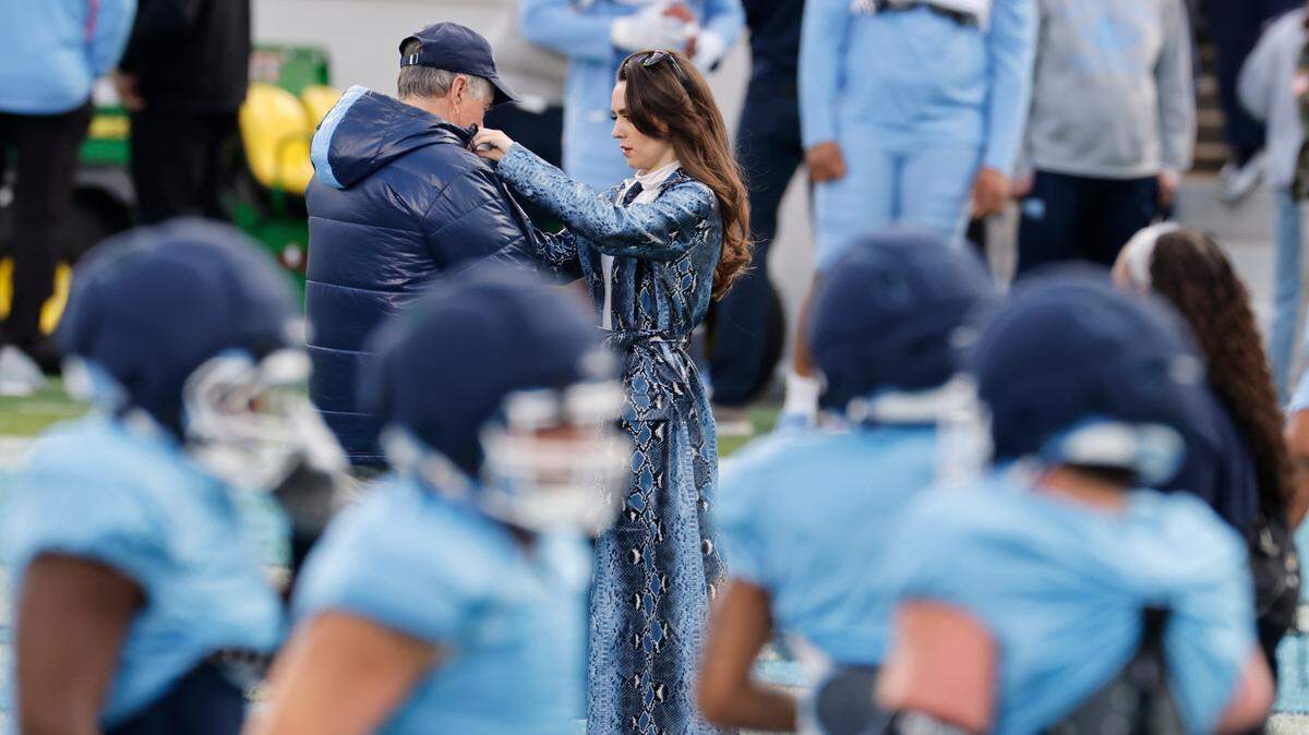 Jordon Hudson, girlfriend of UNC football coach Bill Belichick, adjusts his coat during UNC football’s Practice Like a Pro open practice at Kenan Stadium in Chapel Hill, N.C., Saturday, April 12, 2025.