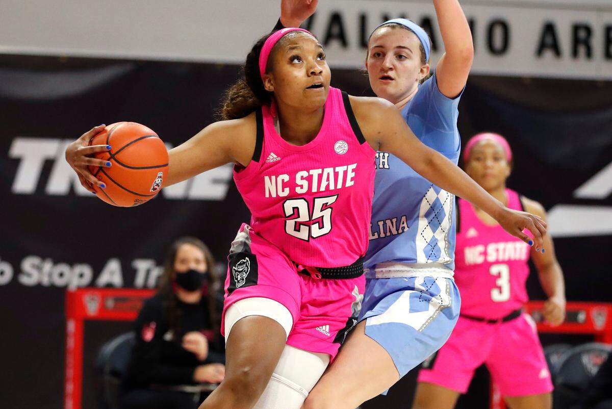 N.C. State’s Kayla Jones (25) drives around North Carolina’s Alyssa Ustby (1) during the second half of N.C. State’s 82-63 victory over UNC in the annual Play4Kay game at Reynolds Coliseum in Raleigh, N.C., Sunday, February 21, 2021.