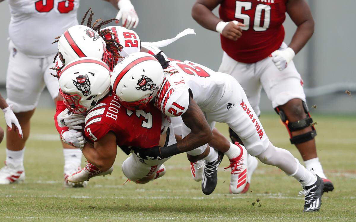 N.C. State’s Khalid Martin (21) and Sean Brown (29) tackle running back Jordan Houston (3) during the Wolfpack’s spring game at Carter-Finley Stadium in Raleigh, N.C., Saturday, April 10, 2021.