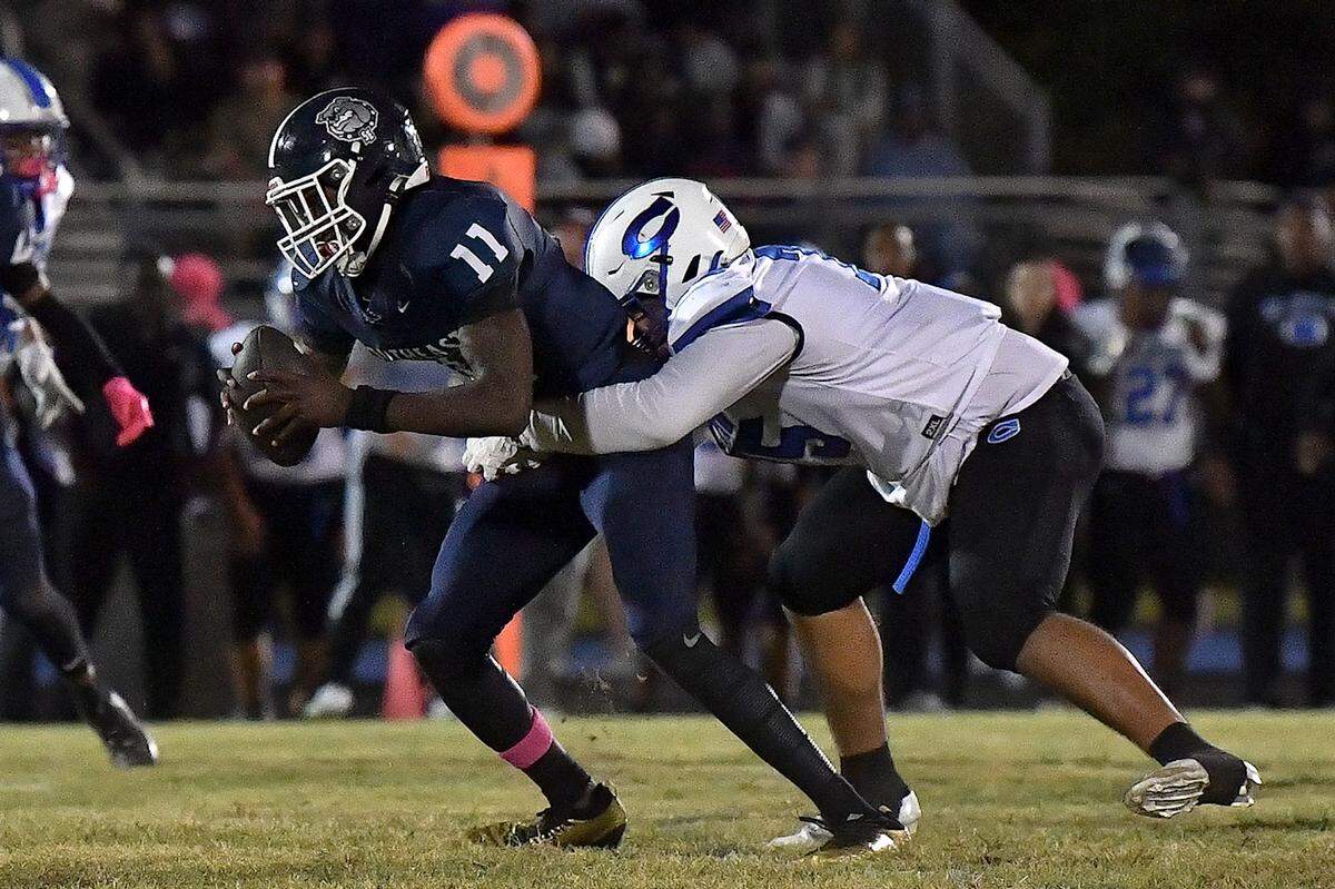 Southeast Raleigh defensive end Keysaun Eleazer (11) made the interception and is grappled by Clayton's Cory Robinson (75) during the second half. The Southeast Raleigh Bulldogs and the Clayton Comets met in a non-conference football game in Raleigh, N.C. October 3, 2025