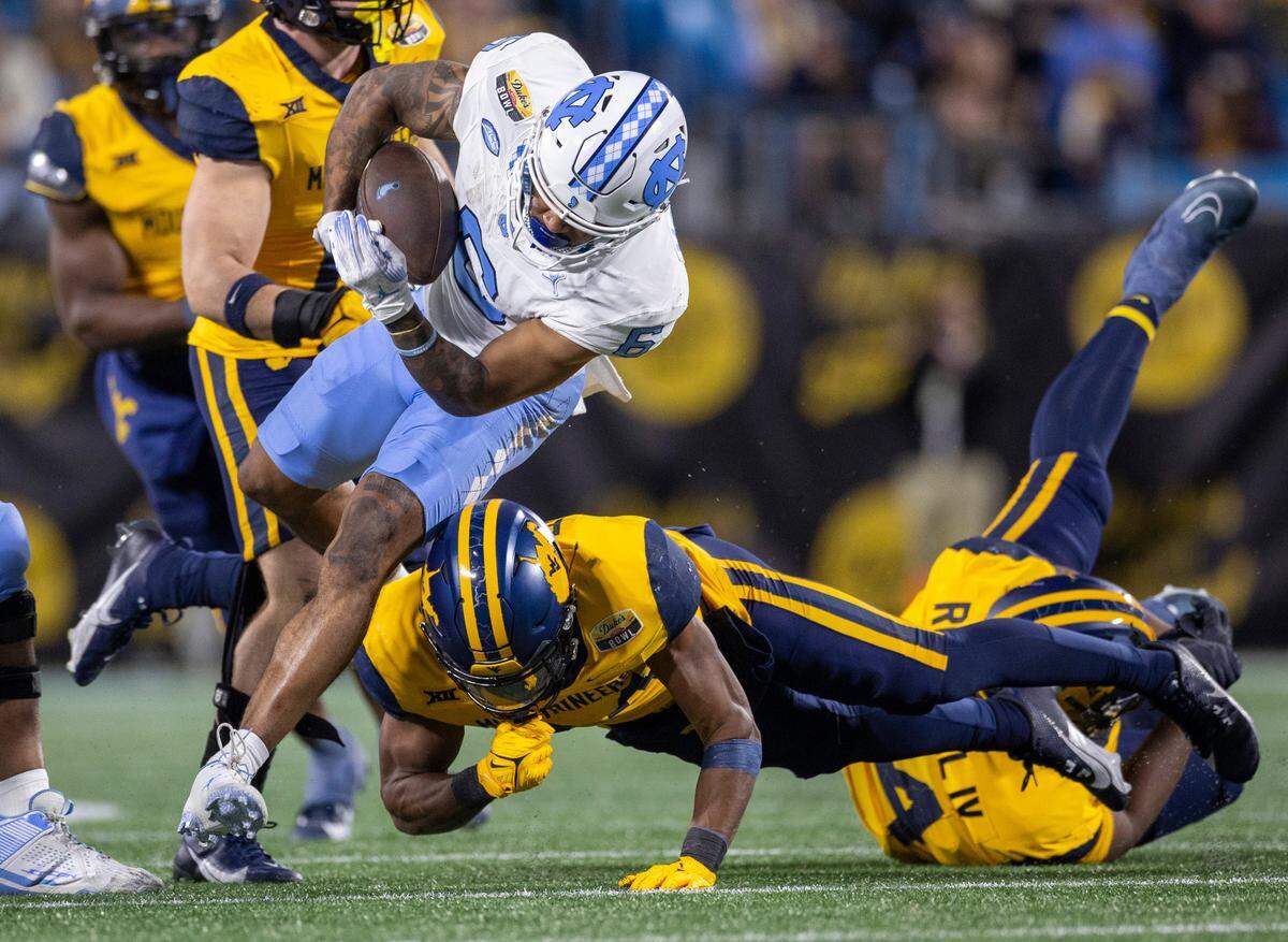 North Carolina’s Nate McCollum (6) is stopped by West Virginia’s Marcis Floyd (24) after a 13-yard pass completion from quarterback Conner Harrell in the third quarter during the Duke’s Mayo Bowl on Wednesday, December 27, 2023 at Bank of American Stadium in Charlotte, N.C.