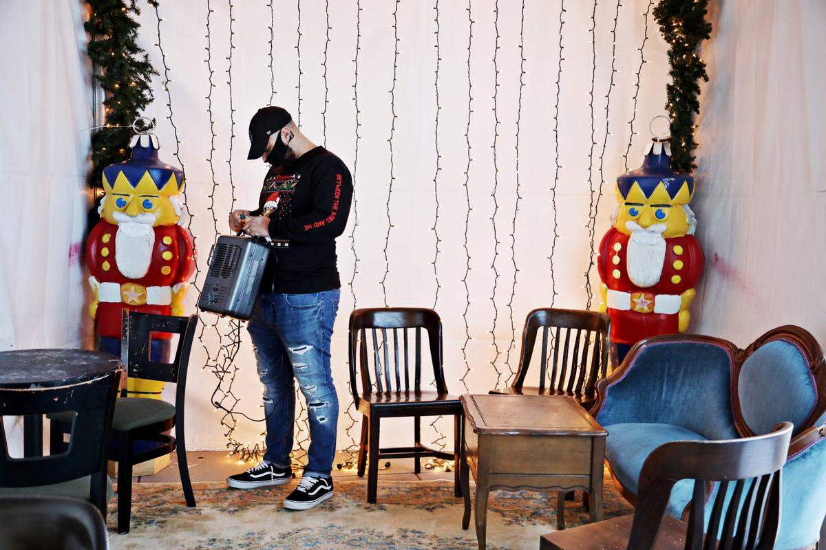 Haymaker bartender Christian Gibbs helps with finishing touches to the tent outside of the Raleigh bar on Tuesday, Dec. 1, 2020.