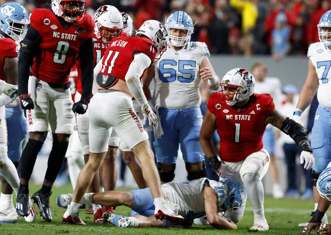 N.C. State’s Payton Wilson (11) and Davin Vann (1) stand over North Carolina quarterback Drake Maye (10) after tackling him during the first half of N.C. State’s game against UNC at Carter-Finley Stadium in Raleigh, N.C., Saturday, Nov. 25, 2023.