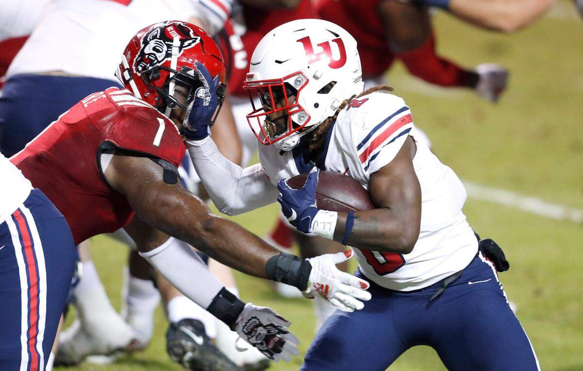 Liberty running back Joshua Mack (8) tries to get by N.C. State linebacker Isaiah Moore (1) during the first half of N.C. State’s game against Liberty at Carter-Finley Stadium in Raleigh, N.C., Saturday, Nov. 21, 2020.