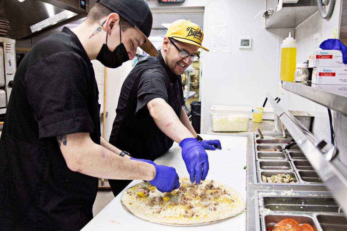 Chef Sam Paskoff, right, and sous chef Josh Springer, left, make a Curry Cubano on Wednesday, March 9, 2022, at Trophy Brewing & Pizza. Trophy boasts one of the Triangle’s most creative pizza menus and was a pioneer in Detroit-style pies that are now all the rage.