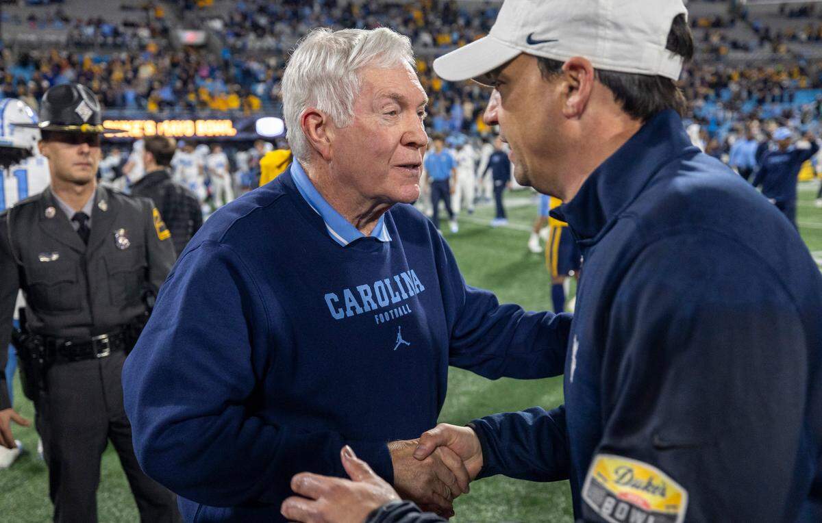North Carolina coach Mack Brown congratulates West Virginia coach Neal Brown following the Mountaineers’ 30-10 victory in the Duke’s Mayo Bowl on Wednesday, December 27, 2023 at Bank of American Stadium in Charlotte, N.C.