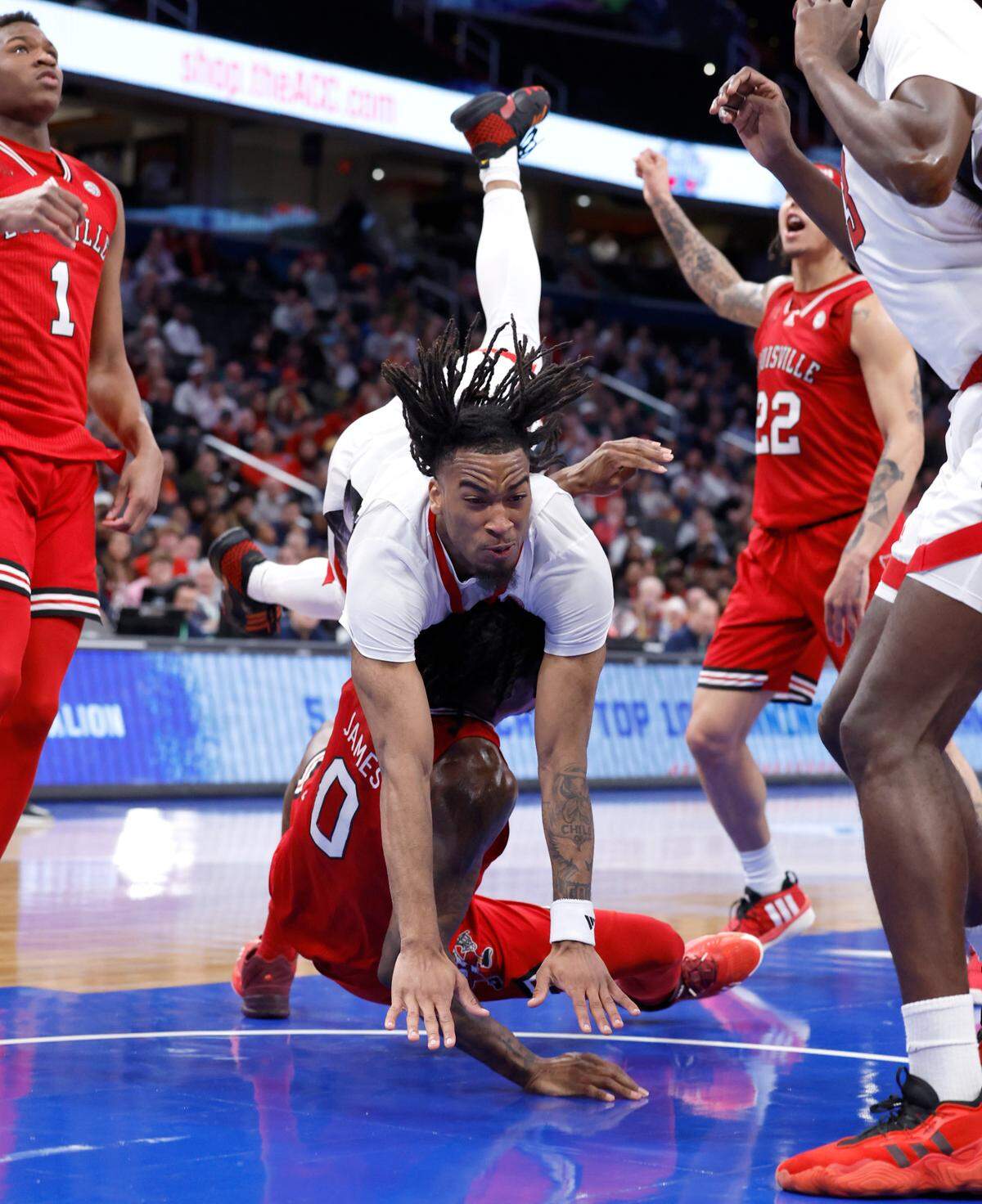 N.C. State’s Jayden Taylor (1) goes over Louisville’s Mike James (0) after he was fouled by James during the first half of N.C. State’s game against Louisville in the first round of the 2024 ACC Men’s Basketball Tournament at Capital One Arena in Washington, D.C., Tuesday, March 12, 2024.