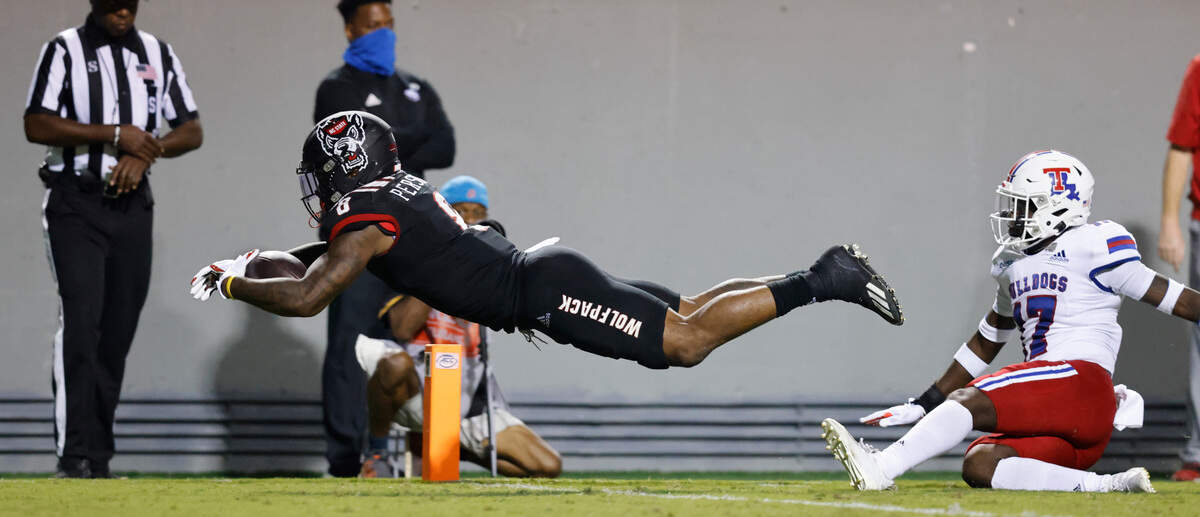 N.C. State running back Ricky Person Jr. (8) dives for a touchdown on a 24-yard run during the second half of N.C. State’s 34-27 victory over Louisiana Tech at Carter-Finley Stadium in Raleigh, N.C., Saturday, October 2, 2021. Louisiana Tech defensive back Brodrick Calhoun (17) is to the right.