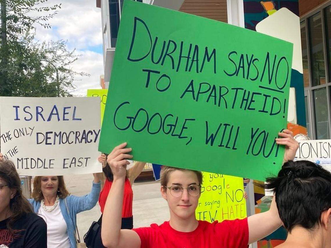 Namoi Busenitz (front) and Marcia Harris (back) hold contrasting signs during a Sept. 8 protest outside Google’s office in downtown Durham.