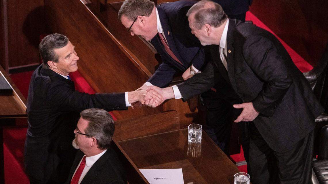 Gov. Roy Cooper, left, shakes hands with House Speaker Tim Moore, center and Senate Leader Phil Berger prior to Cooper’s biennial State of the State address to a joint session of the General Assembly at the Legislative Building Monday evening, Feb. 26, 2019.
