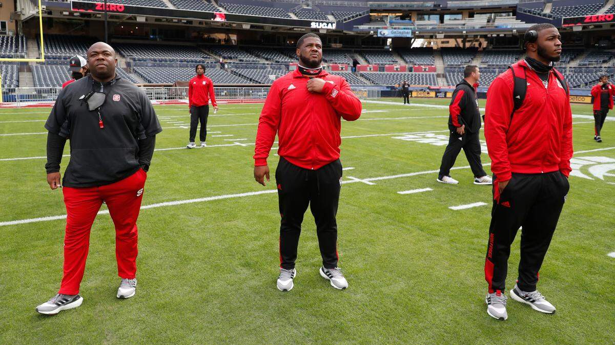 From left, N.C. State’s Dantonio Burnette, director of strength and conditioning, center Grant Gibson and linebacker Isaiah Moore look over Petco Park as the N.C. State football team tours the field in San Diego, CA Monday, Dec. 27, 2021, a day before the Holiday Bowl.