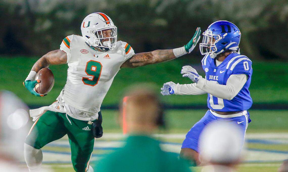 Miami Hurricanes tight end Brevin Jordan (9) carries the football as Duke Blue Devils safety Marquis Waters (0) closes in the first half at Wallace Wade Stadium Saturday, Dec. 5, 2020.