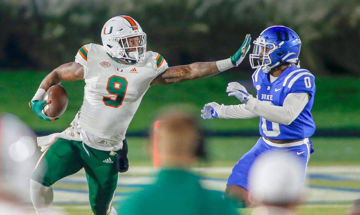 Former Miami Hurricanes tight end Brevin Jordan (9) carries the football as Duke Blue Devils safety Marquis Waters (0) closes in the first half at Wallace Wade Stadium Saturday, Dec. 5, 2020.