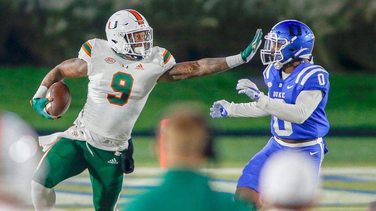 Miami Hurricanes tight end Brevin Jordan (9) carries the football as Duke Blue Devils safety Marquis Waters (0) closes in the first half at Wallace Wade Stadium Saturday, Dec. 5, 2020.