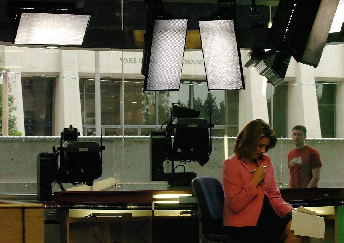A passerby looks in as WTVD reporter/anchor Frances Scott finishes a 5:30 p.m. newscast from the ABC11 studio in downtown Raleigh in 2009.