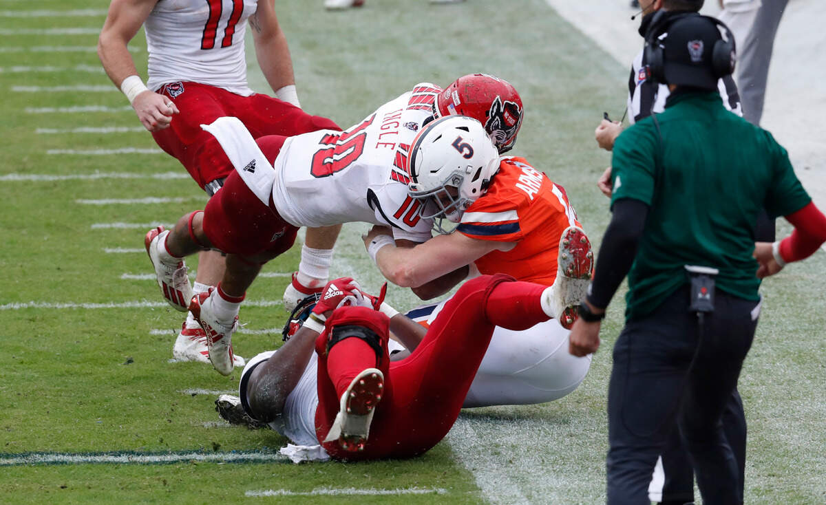 N.C. State safety Tanner Ingle (10) hits Virginia quarterback Brennan Armstrong (5) during the first half of N.C. State’s game against Virginia at Scott Stadium in Charlottesville, Va., Saturday, Oct. 10, 2020. Ingle was called for targeting and Armstrong left the game.