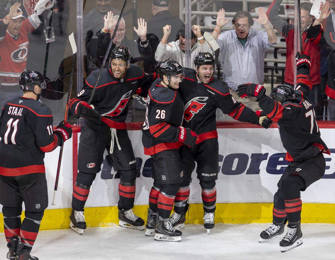 Carolina Hurricane left wing Jordan Martinook (48) celebrates with Sean Walker (26), Taylor Hall and fellow teammates after scoring the game winning goal in the second overtime to secure a 3-2 victory over Ottawa in Game 2 on Monday, April 20, 2026 during the first round of the Stanley Cup Playoffs at Lenovo Center in Raleigh, N.C.