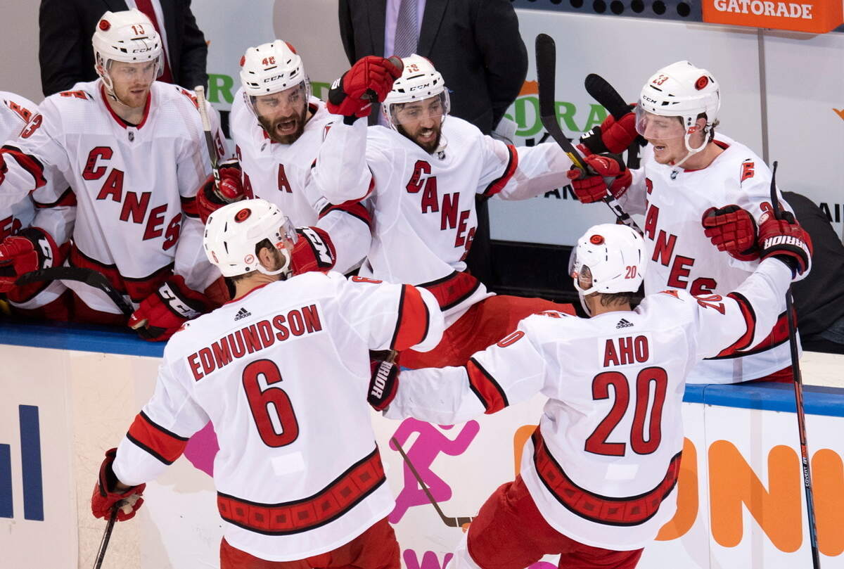 Carolina Hurricanes center Sebastian Aho (20) is congratulated by teammates Joel Edmundson (6) , Warren Foegele (13), Jordan Martinook (48), Vincent Trocheck (16) and Brock McGinn (23) after scoring against the New York Rangers during the third period of an NHL hockey playoff game Tuesday, Aug. 4, 2020, in Toronto. (Frank Gunn/The Canadian Press via AP)