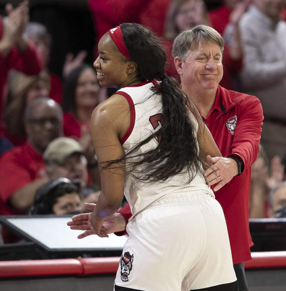N.C. State coach Wes Moore embraces Kayla Jones (25) as she comes out of the game in the closing minutes after leading the Wolfpack with 18 points in their 89-57 victory against Kansas State during the second round of the NCAA Tournament on Monday, March 21, 2022 at Reynolds Coliseum in Raleigh, N.C.