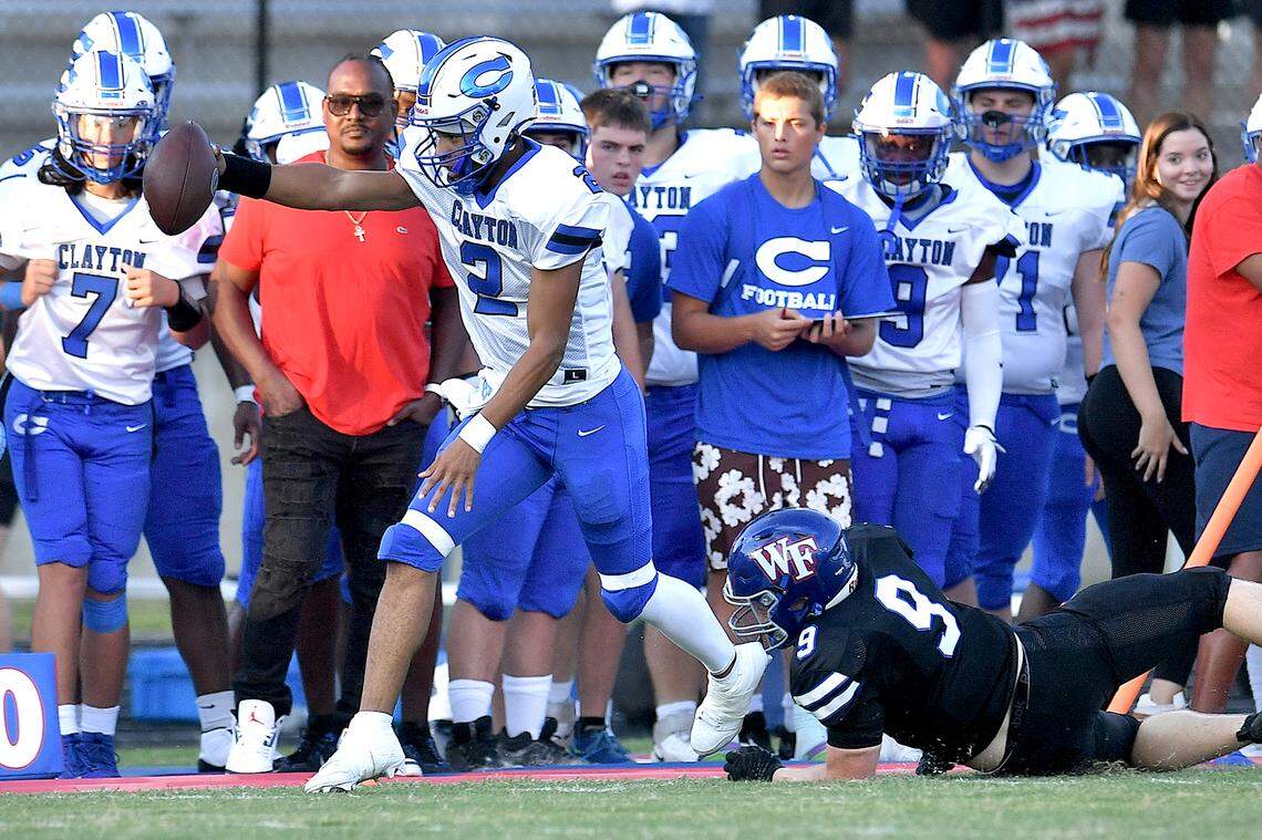 Clayton quarterback Aiden Smalls (2) runs for the first down ahead of Wake Forest’s Holden Sweeney (9) during the first half. The Wake Forest Cougars and the Clayton Comet met in a non-conference football game in Wake Forest, N.C. on August 23, 2024.