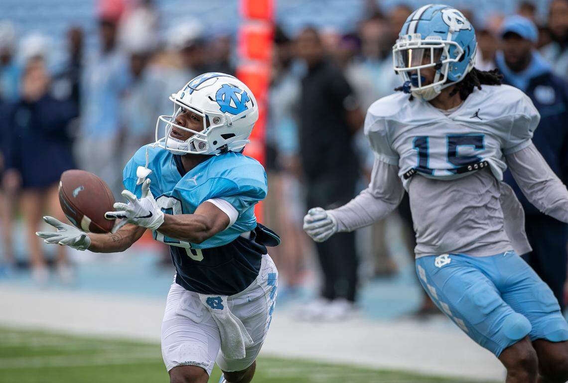 North Carolina wide receiver Tychaun Chapman (0) works to pull in a pass from quarterback Connor Harrell (15) ahead of defensive back Ladaeson Hollins (15) during a scrimmage at the Tar Heels’ open practice on Saturday, March 25, 2023 at Kenan Stadium in Chapel Hill. N.C.