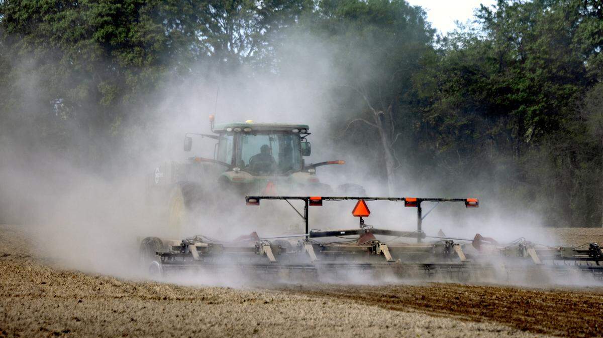 A cloud of dust envelopes a farmer and his tractor as he tills a field between Smithfield and Goldsboro, Saturday, April 4, 2026.