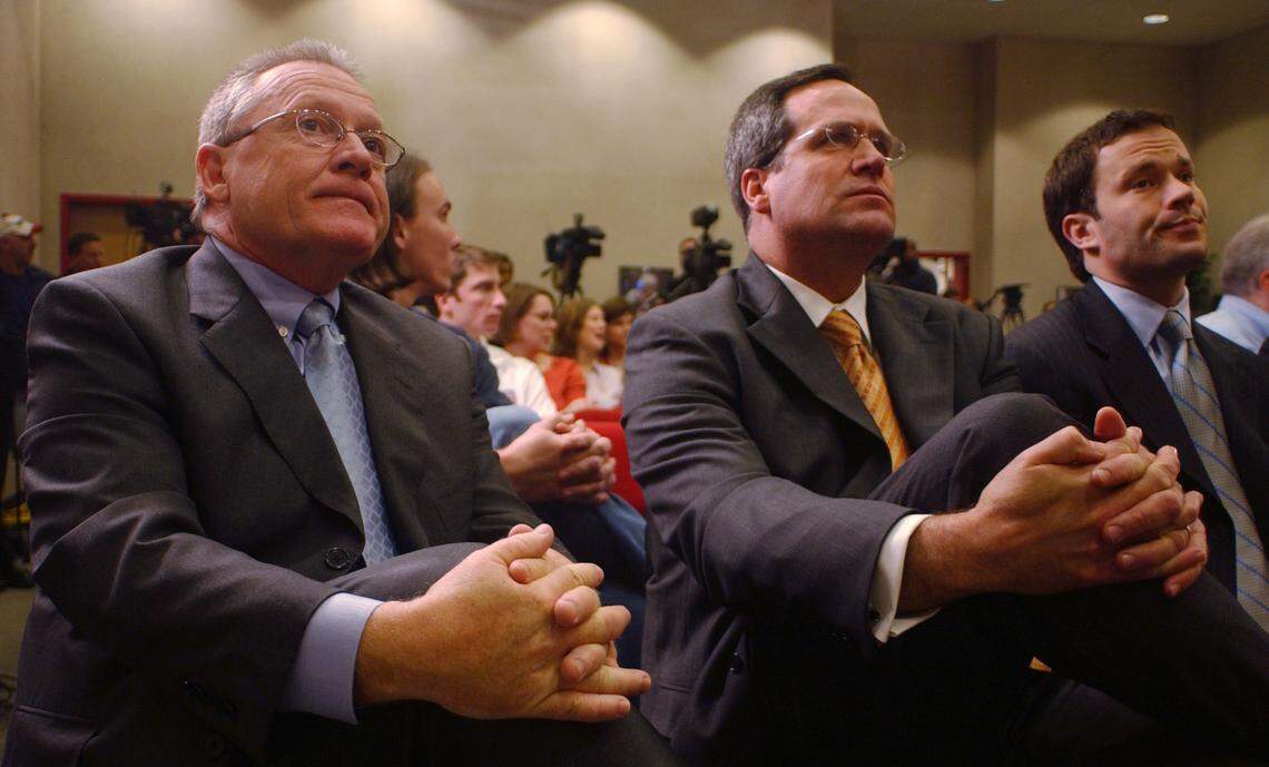 Then-Carolina Hurricanes General Manager Jim Rutherford, left, Matt West, vice president of business operations, and Jason Karmanos, vice president and assistant general manager, watch a televised news conference as NHL Commissioner Gary Bettman announces the cancellation of the 2005 season, Feb. 16, 2005.