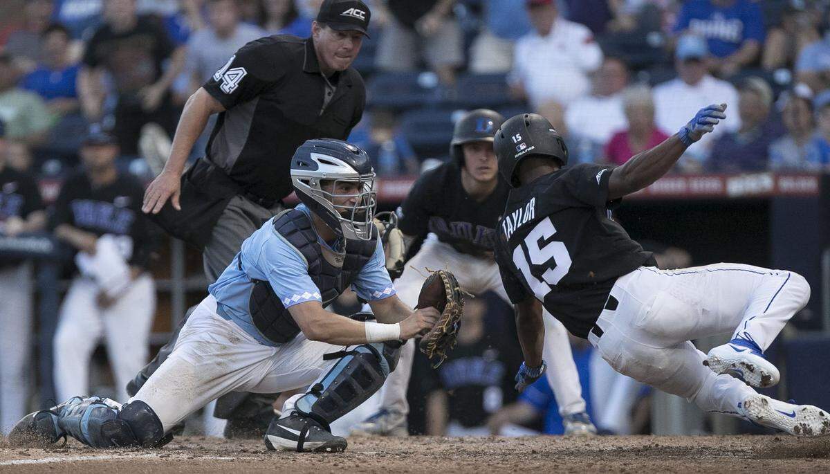 Duke's Kennie Taylor (15) scores on a single by Jimmy Herron in the bottom of the fifth inning to give Duke a 3-0 lead over North Carolina on Friday, May 11, 2018, at the Durham Bulls Athletic Park in Durham, N.C. North Carolina catcher Brandon Martorano (4) missed the tag, the play was reviewed and Taylor was called safe.